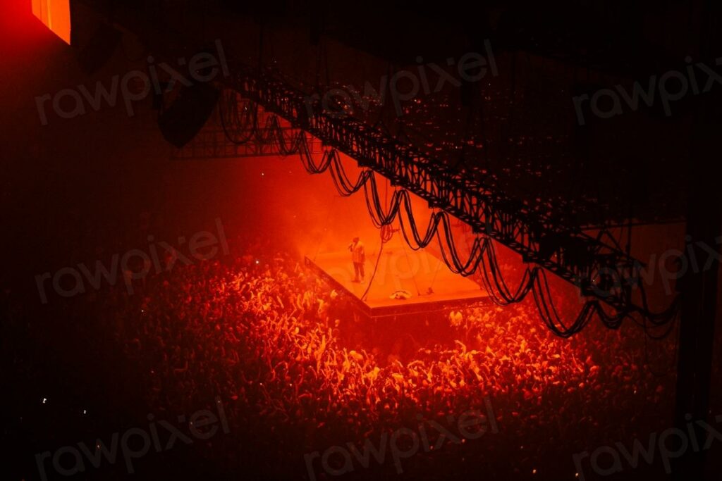 A high shot of a crowd - a crowd of people are gathered around a stage