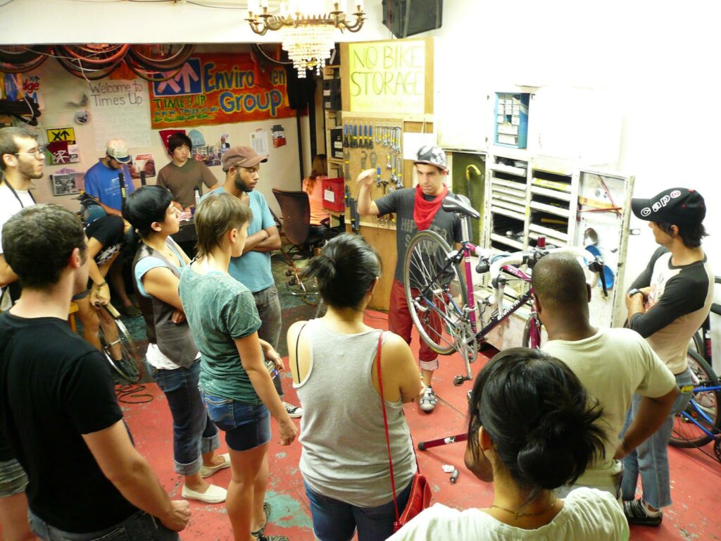 File:Time's Up! Bike Repair Class.jpg - a group of people standing around a room