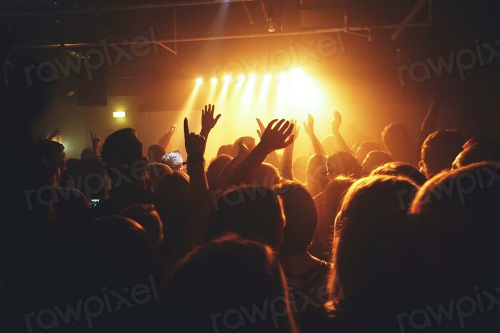 Free concert image - a crowd at a concert with their hands up